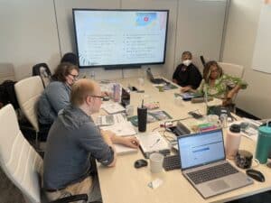 working group sitting in conference room with laptops and papers